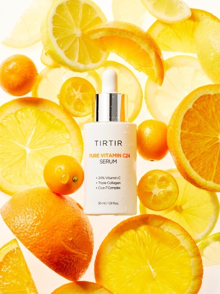 A top-down, clean product shot of a Tirtir Pure Vitamin C24 Serum bottle surrounded by floating slices of lemons and oranges, emphasizing freshness.